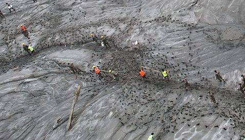A drone view shows rescue workers inspecting damaged structures amid sludge, debris and landslides in the aftermath of flash flooding.