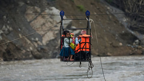 A young girl with her parents commutes across the Trishuli river on a newly installed zipline in the aftermath of flash floods at Bidur, Nuwakot district, Nepal, Saturday, Sept. 5, 2026.