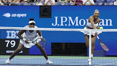 USA's Serena Williams serves during the women's doubles first-round tennis match, playing alongside her sister Venus Williams (L)