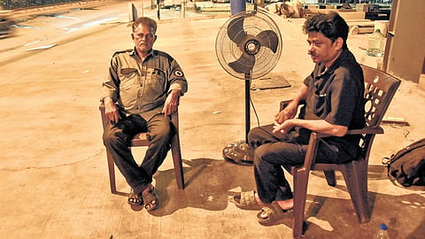 Night watchmen use a pedestal fan as heat lingers in Vijayawada