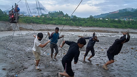 Residents commute across the Trishuli river on a newly installed zipline in the aftermath of flash floods at Bidur, Nuwakot district, Nepal, Saturday, Sept. 5, 2026.