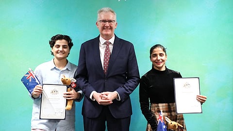 Fatemeh Pasandideh, left, and Atefeh Ramezanisadeh, right, former members of the Iranian women's soccer team, stand with Australia's Minister for Home Affairs, Tony Burke, after receiving their citizenship in Brisbane, Australia, on Aug. 5, 2026.