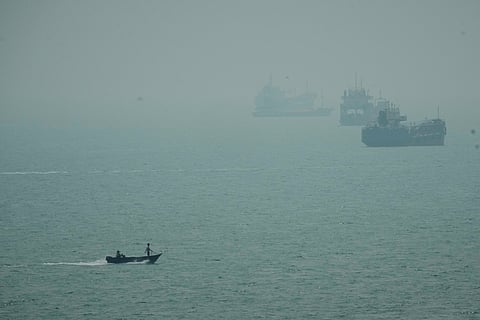 A motorboat travels past commercial vessels anchored amid haze in the Strait of Hormuz off Bandar Abbas, Iran, Monday, Sept. 7, 2026