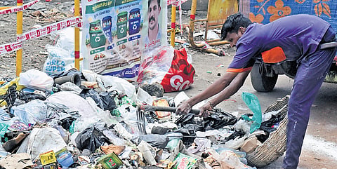 A pourakarmika collects garbage from the roadside on Tuesday