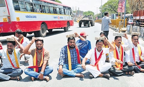 Kannada activists protest by placing stones on their head against the CWRC order on releasing water to Tamil Nadu, in Mandya on Wednesday.