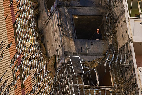 A woman peers from a window of a partially damaged residential building following a Russian drone attack in Kyiv, Ukraine, Wednesday, Sept. 9, 2026.