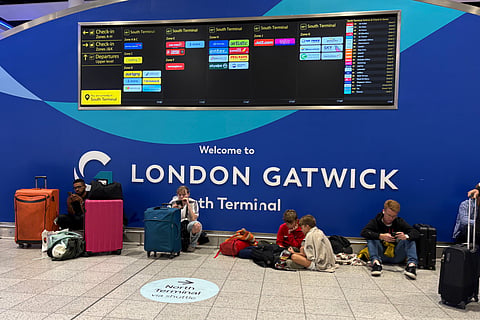 Passengers at Gatwick Airport's South Terminal sit after flights were cancelled because of a technical issue in Britain's air traffic control system Tuesday, Sept. 8, 2026, in Crawley, south of London.