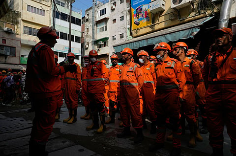 An officer with India's National Disaster Response Force (NDRF), left, briefs his team during a rescue operation at the site of a collapsed building in New Delhi, India, Monday, Sept. 7, 2026.