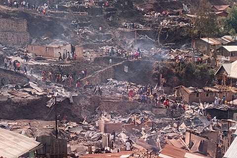 People walk amid the charred remains of homes near a primary school and a secondary school where a fire broke out, killing several students, in Bukavu, Congo, Thursday, Sept. 10, 2026.
