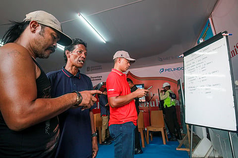 Families members of affected passengers read updates on a whiteboard on ongoing rescue operations on the stricken Virgo Transport 8 ferry, at Trisakti Bandarmasih Port in Banjarmasin, South Kalimantan, on September 13, 2026.