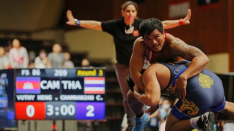 Kirtisna Arya (in the background) officiating during a bout