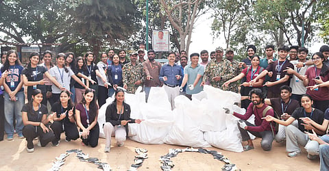 Ploggers pose with the waste collected during a clean-up drive at Madiwala Lake in Bengaluru on Saturday