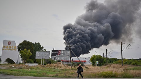 A woman walks by the burning warehouse at the city entrance following Russian air attack in Odesa, Ukraine, Sunday, Sept. 13, 2026.