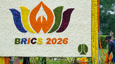 A worker arranges flowers around a floral welcome board of the 18th BRICS Summit set up by the New Delhi Municipal Council (NDMC) at Mandi House, in New Delhi, Friday, Sept. 11, 2026.