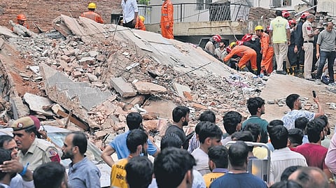 National Disaster Response Force (NDRF) personnel clear rubble during rescue operations following the collapse of a multi-storey building housing a PG, at Satya Niketan, in New Delhi.