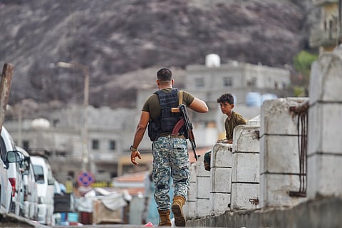 An armed man walks past a boy at the Sirah fish market in Aden, Yemen, Tuesday, Sept. 15, 2026.