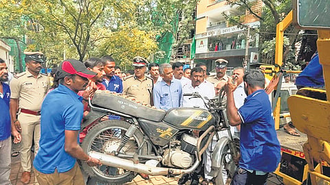 Minister Krishna Byre Gowda and City Police Commissioner Seemant Kumar Singh oversee the shifting of impounded vehicles from Jayanagar Police Station on Wednesday.