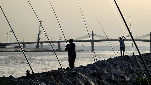 A man fishes with a net along a beach in La Goulette on the eastern outskirts of Tunis on August 24, 2026.