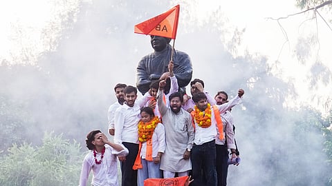Akhil Bharatiya Vidyarthi Parishad's (ABVP) Yash Dabas, Riya Chhawdi and Lakshay Raj Singh celebrate with others as they climb atop Swami Vivekanand's statue after winning three of the four central panel posts in the Delhi University Students' Union (DUSU) elections, at the Faculty of Arts, in New Delhi, Saturday, Sept. 19, 2026.