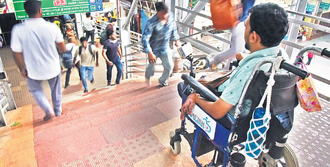 A man on a wheelchair is stranded after the foot over bridge ends in steps leading to a platform at the railway station