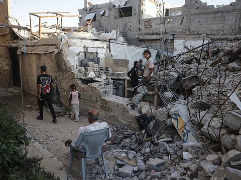 Displaced Palestinians gather amid the rubble of a heavily damaged building being used as a shelter in Khan Yunis in the southern Gaza Strip on September 19, 2026.