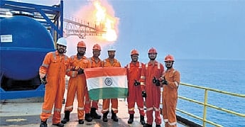 ONGC workers flaunt the National flag after striking gas at the well.