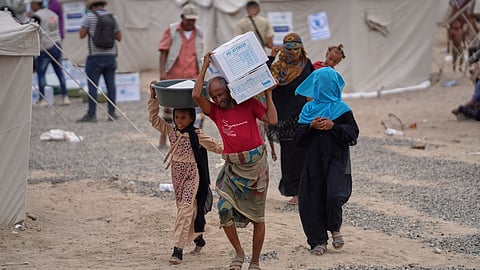Displaced Yemenis carry emergency aid supplies at Al-Firdaws camp in Ras Imran, on the western outskirts of Aden, Yemen, Thursday, Sept. 17, 2026.