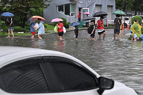 People walk through flood waters along Phetchaburi Road in Bangkok on September 26, 2026.
