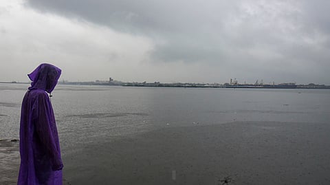 A man covers himself during rainfall as monsoon arrives, at Marine Drive, in Kochi, Kerala, Friday, June 5, 2026.