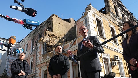Ukraine's President Volodymyr Zelenskyy, centre, and German Chancellor Friedrich Merz speak to media with National Academy of science building damaged after a Russian drone strike, on the background, Kyiv, Ukraine, Sunday, Oct. 4, 2026.