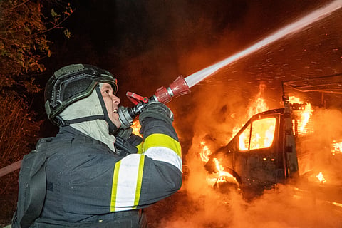 A rescue worker tries to put out a fire of a residential house damaged in a Russian drone strike on Kharkiv, Ukraine, Sunday, Oct. 4, 2026.