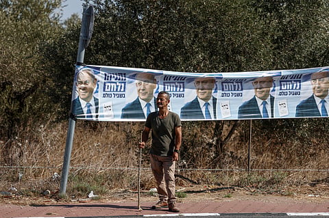 A Palestinian farmer stands next to an election banner featuring Israel's Prime Minister Benjamin Netanyahu near the Palestinian-owned olive groves in the village of Rantes near Ramallah, in the Israeli-occupied West Bank on October 6, 2026.