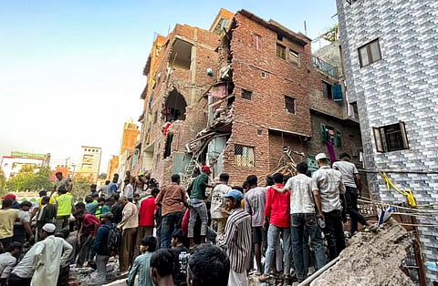 People gather on site after a four-storey building collapsed, with debris burying portions of two to three adjoining houses, in the Seemapuri area, New Delhi, Wednesday, Oct. 7, 2026. At least five people were injured and several others are feared trapped.