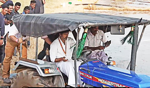 CM Vijay, clad in a white dhoti and shirt, driving a tractor in Madurantakam