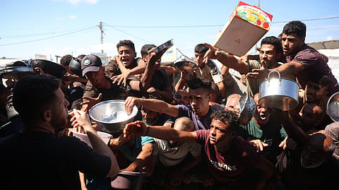 This photo taken on October 6, 2026 shows displaced Palestinians waiting to receive food at a charity kitchen in Khan Yunis, in the southern Gaza Strip.