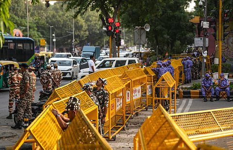 Security personnel stand guard behind multi-layered police barricades set up near Janpath metro station ahead of a proposed protest call by the Cockroach Janta Party (CJP), in New Delhi, Friday, Oct. 9, 2026.