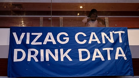 This photograph taken on September 6, 2026, shows an activist standing behind a banner during the People's Convention on AI Data Centres event in Visakhapatnam, Andhra Pradesh.