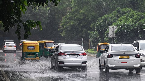 Commuters wade through a rain-slicked road amid heavy rainfall, in New Delhi on Saturday.