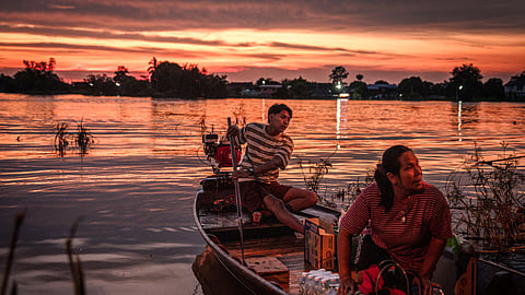 Villagers ride a boat loaded with relief supplies during sunset in Bang Ban district in the central Thai province of Ayutthaya on October 6, 2026.