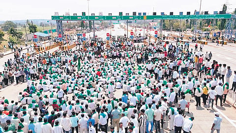 Farmers block National Highway-48 at Hattargi toll plaza along the Karnataka-Maharashtra border on Tuesday.