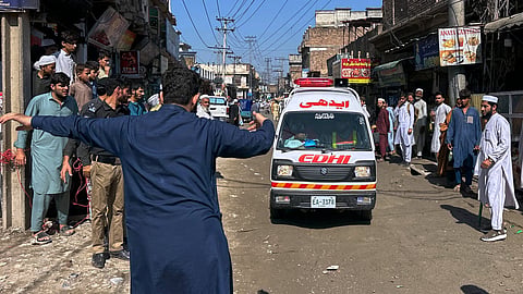 A volunteer clears the way for an ambulance transporting injured school children following a roof collapse at a private school in Peshawar, Pakistan, Thursday, Oct. 15, 2026.