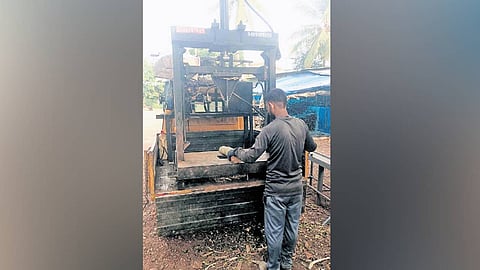 A man operating a hydraulic firewood-splitting machine