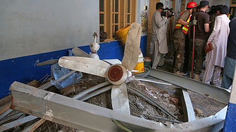 Rescue workers take a break while searching through the rubble at the site of a roof collapse at a private school, in Peshawar, Pakistan, Thursday, Oct. 15, 2026.