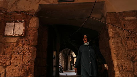 A woman walks beneath a sign that reads in Arabic "Jewish Quarter," in the old city of Sidon, southern Lebanon, Friday, Sept. 25, 2026.