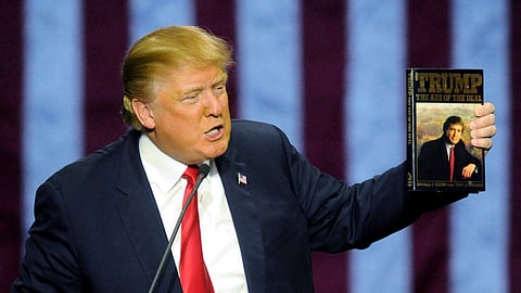 Then-Republican presidential candidate Donald Trump holds up his book "The Art of the Deal", given to him by a fan as he speaks during a campaign stop, Nov. 21, 2015, in Birmingham, Ala.