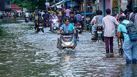 Commuters wade through a waterlogged street following heavy rain in Chennai, Sunday, Oct. 18, 2026.
