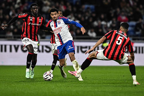 Lyon's Swiss defender #13 Zachary Athekame (C) fights for the ball with Nice's French midfielder #35 Xavier Mandza (L) during the French L1 football match between Olympique Lyonnais (OL) and OGC Nice at the Groupama Stadium in Decines-Charpieu, central-eastern France, on October 18, 2026.