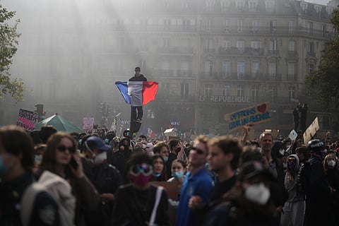 A protester holds a French flag at Republic Square during a demonstration against rising living costs, joining students' grievances, in Paris, Saturday, Oct. 17, 2026.