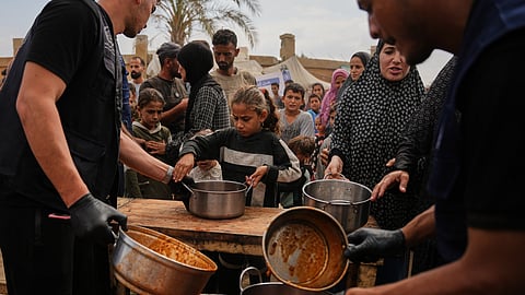 Palestinians receive food donated by the World Food Programme at a displacement camp in Deir al-Balah, in the central Gaza Strip, Sunday, Oct. 18, 2026