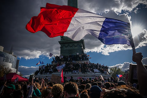 A person holds a French national flag during a protest against under-resourced schools in Paris, Thursday, Oct. 8, 2026.